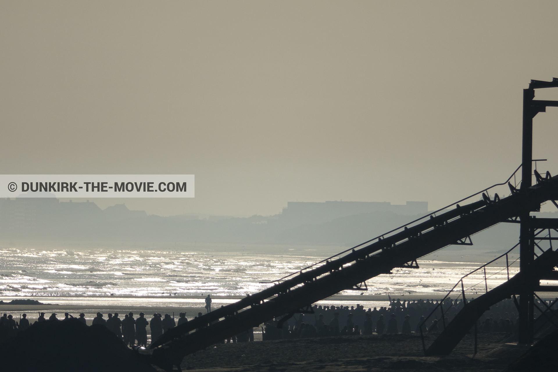 Photo avec ciel orangé, décor, figurants, plage,  des dessous du Film Dunkerque de Nolan