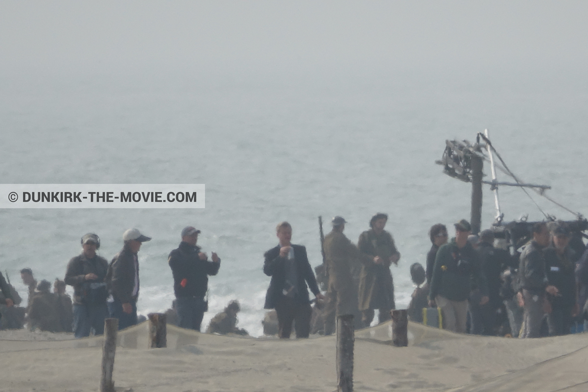 Picture with supernumeraries, Christopher Nolan, beach, technical team,  from behind the scene of the Dunkirk movie by Nolan