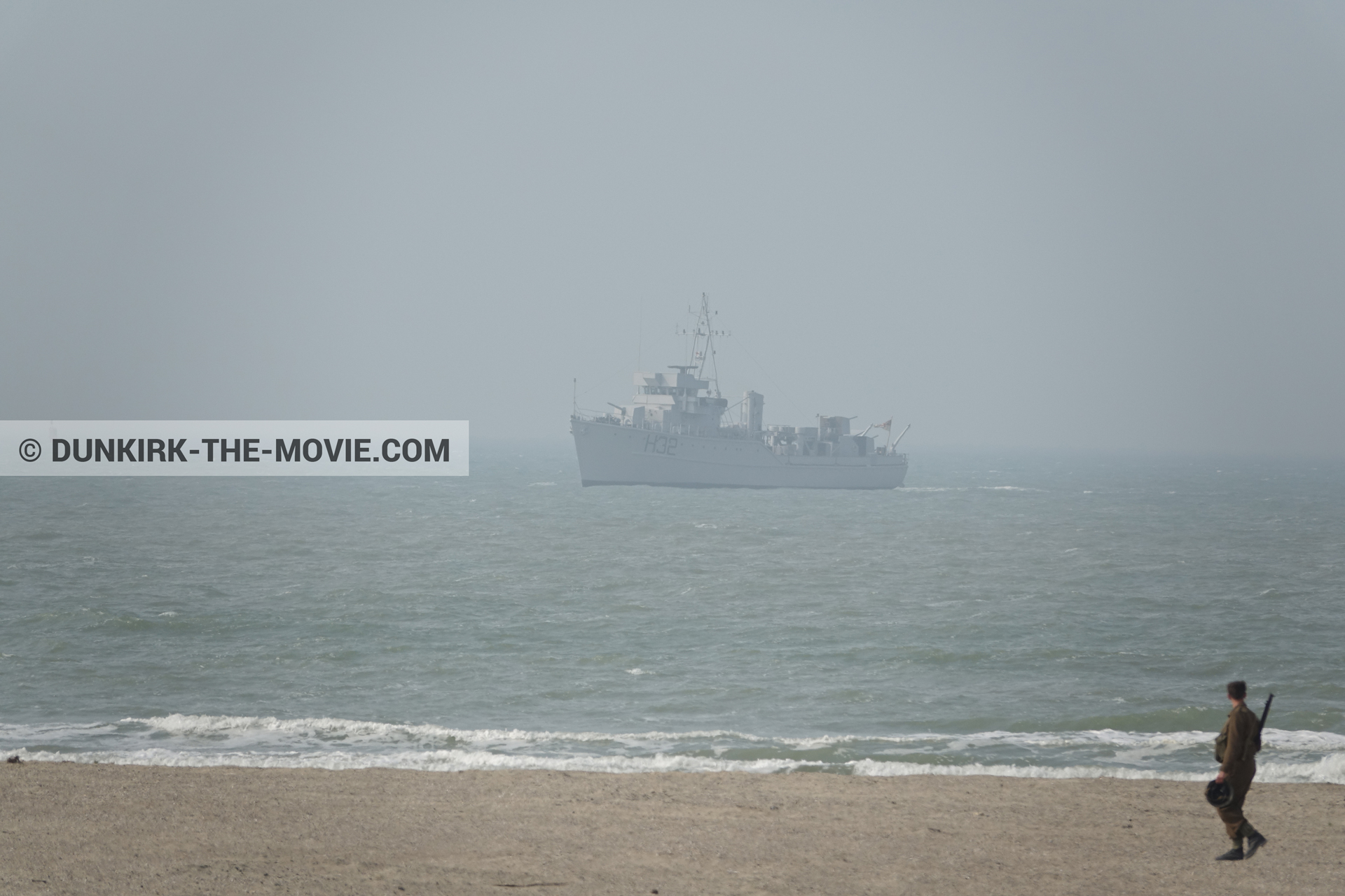 Picture with boat, grey sky, supernumeraries, rough sea, beach,  from behind the scene of the Dunkirk movie by Nolan