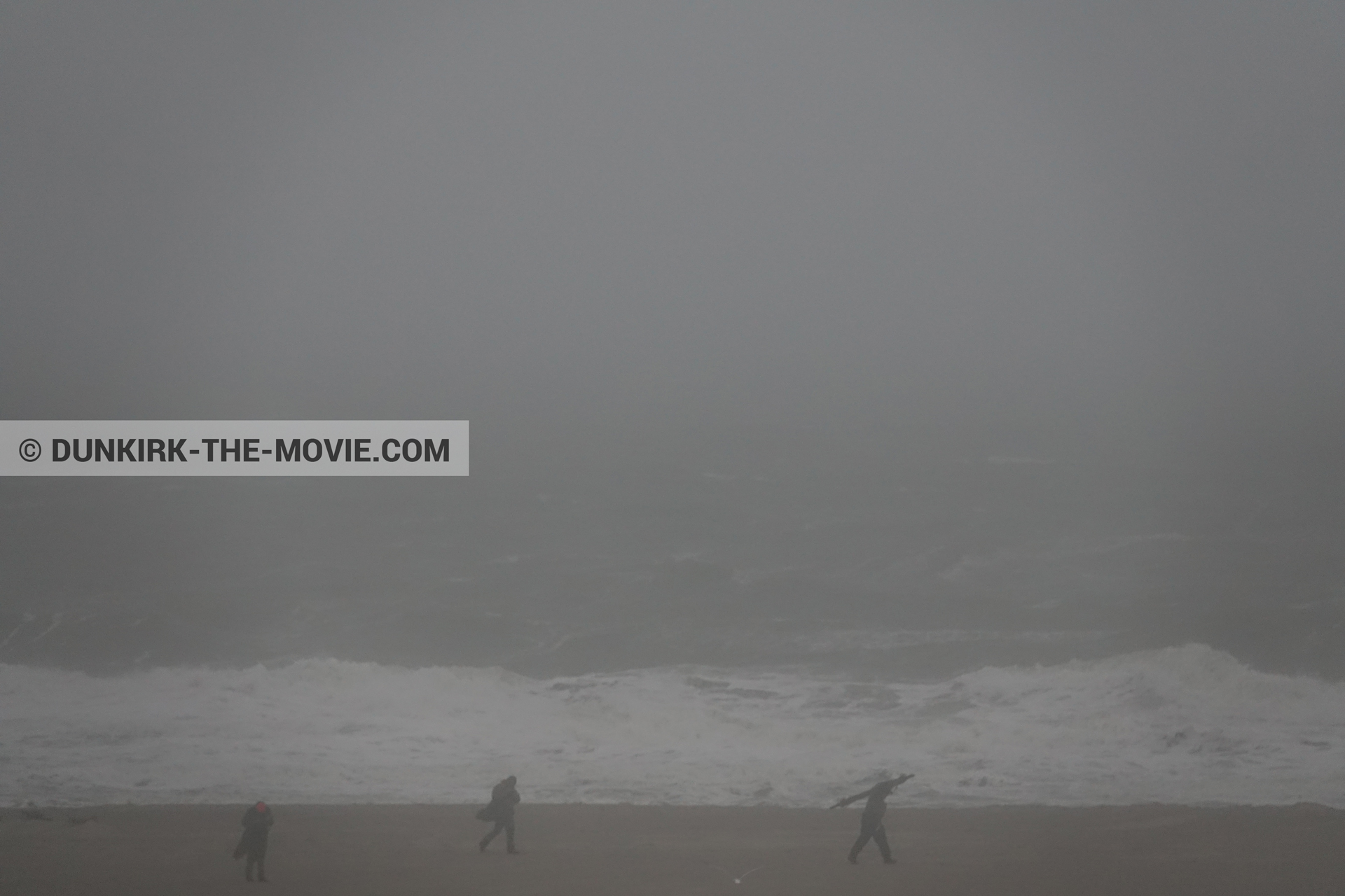 Picture with grey sky, supernumeraries, rough sea, beach,  from behind the scene of the Dunkirk movie by Nolan