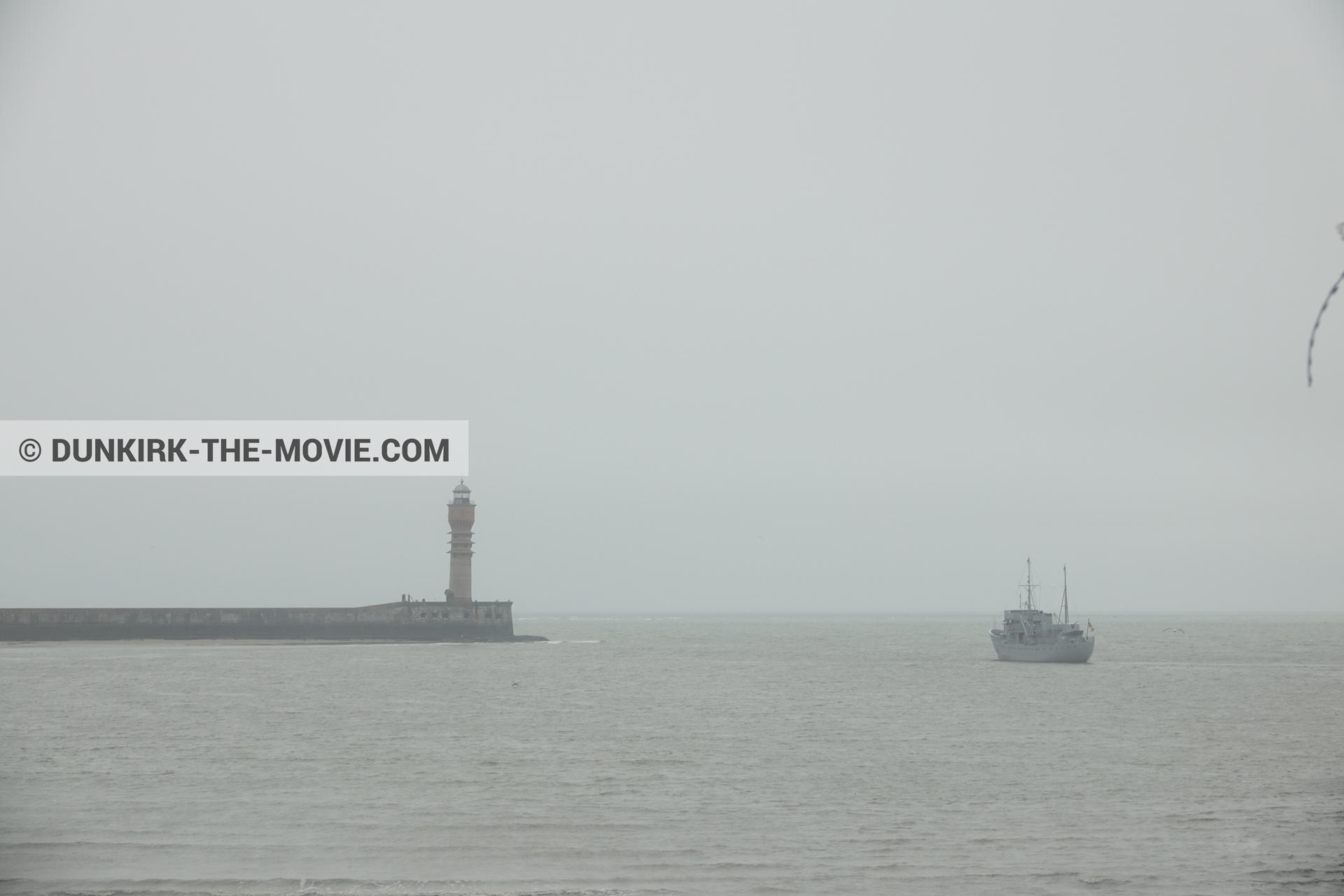 Picture with boat, grey sky, St Pol sur Mer lighthouse,  from behind the scene of the Dunkirk movie by Nolan