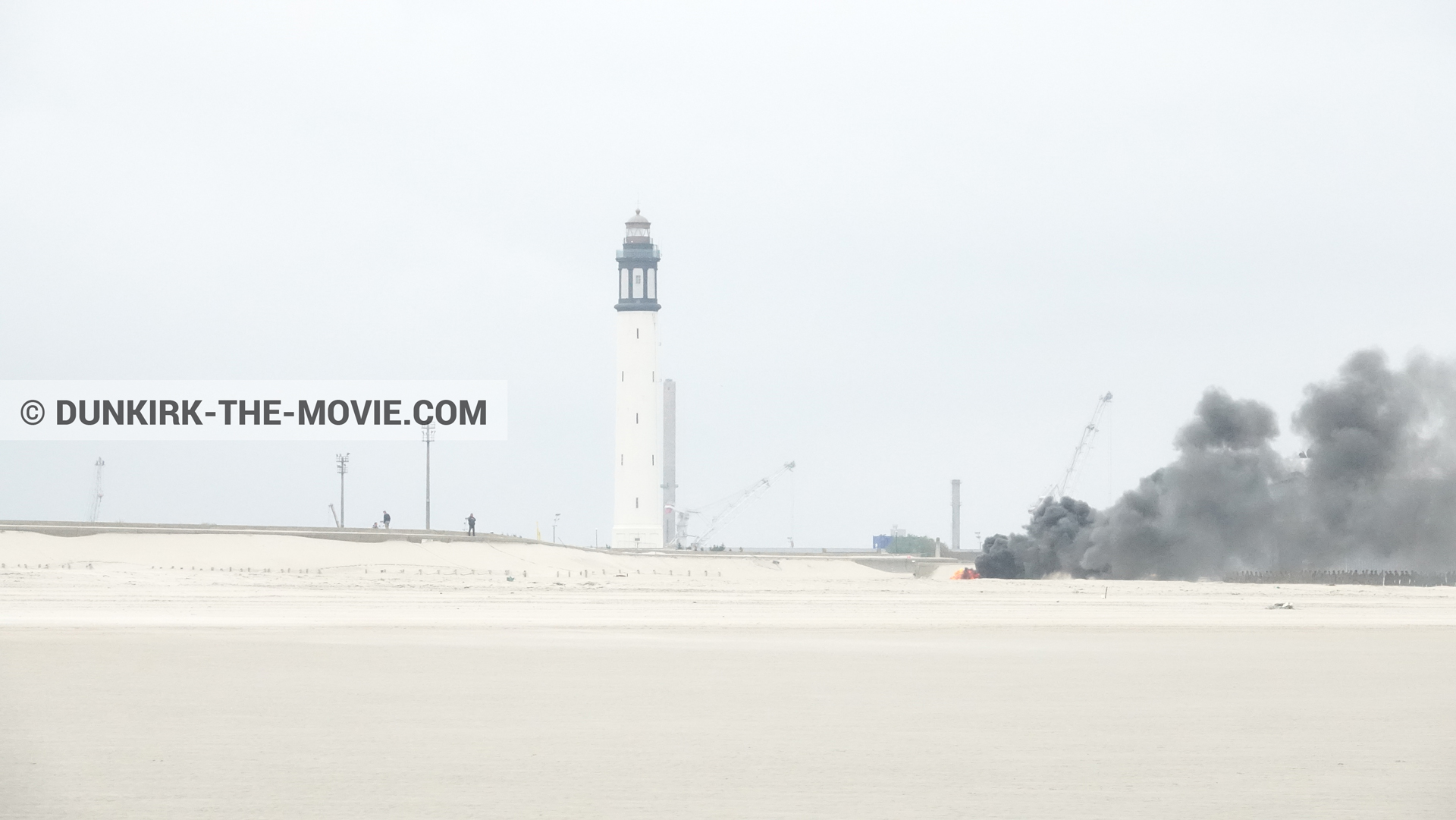 Picture with grey sky, black smoke, Dunkirk lighthouse, beach,  from behind the scene of the Dunkirk movie by Nolan