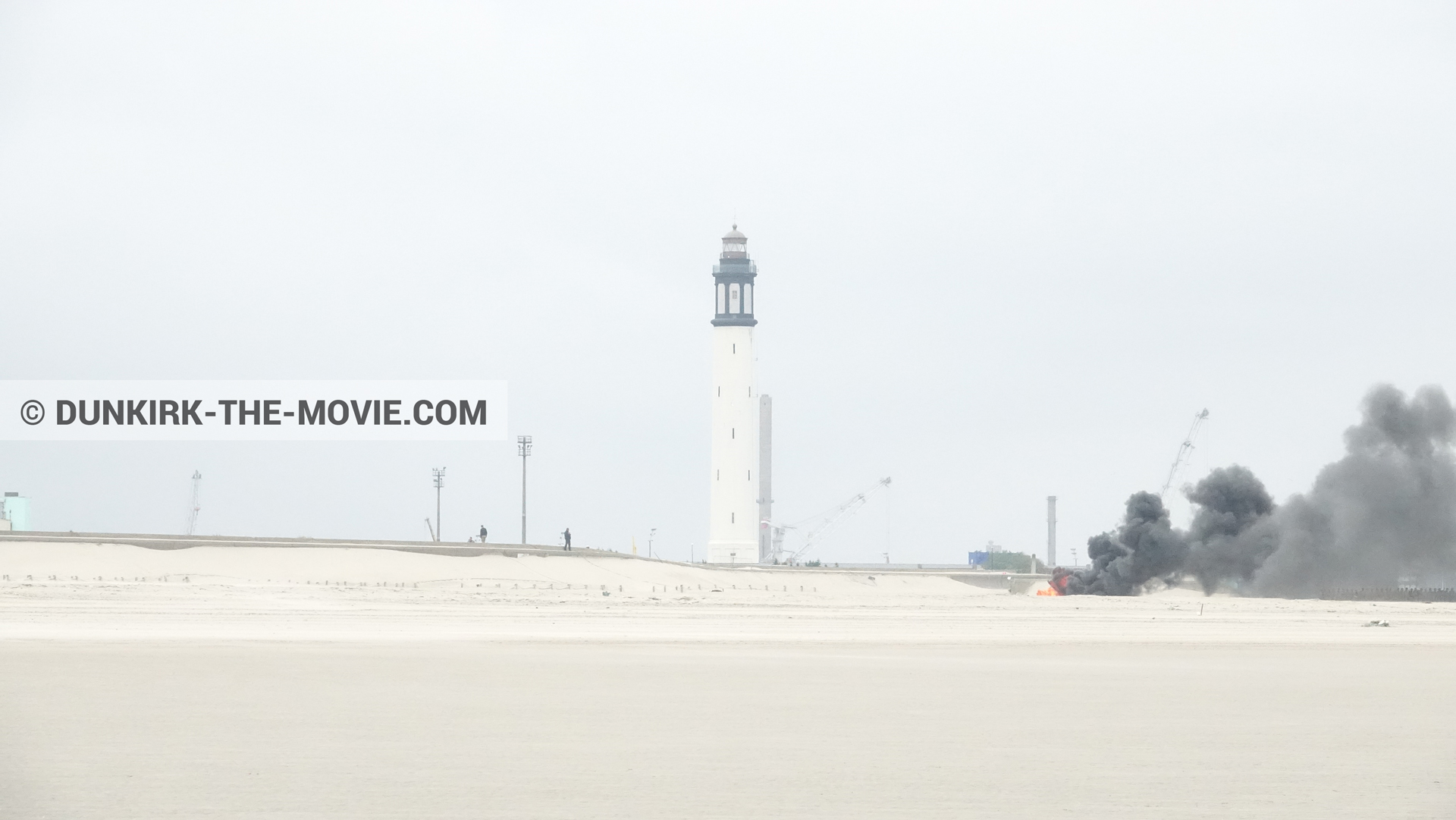 Photo avec ciel gris, fumée noire, phare de Dunkerque, plage,  des dessous du Film Dunkerque de Nolan