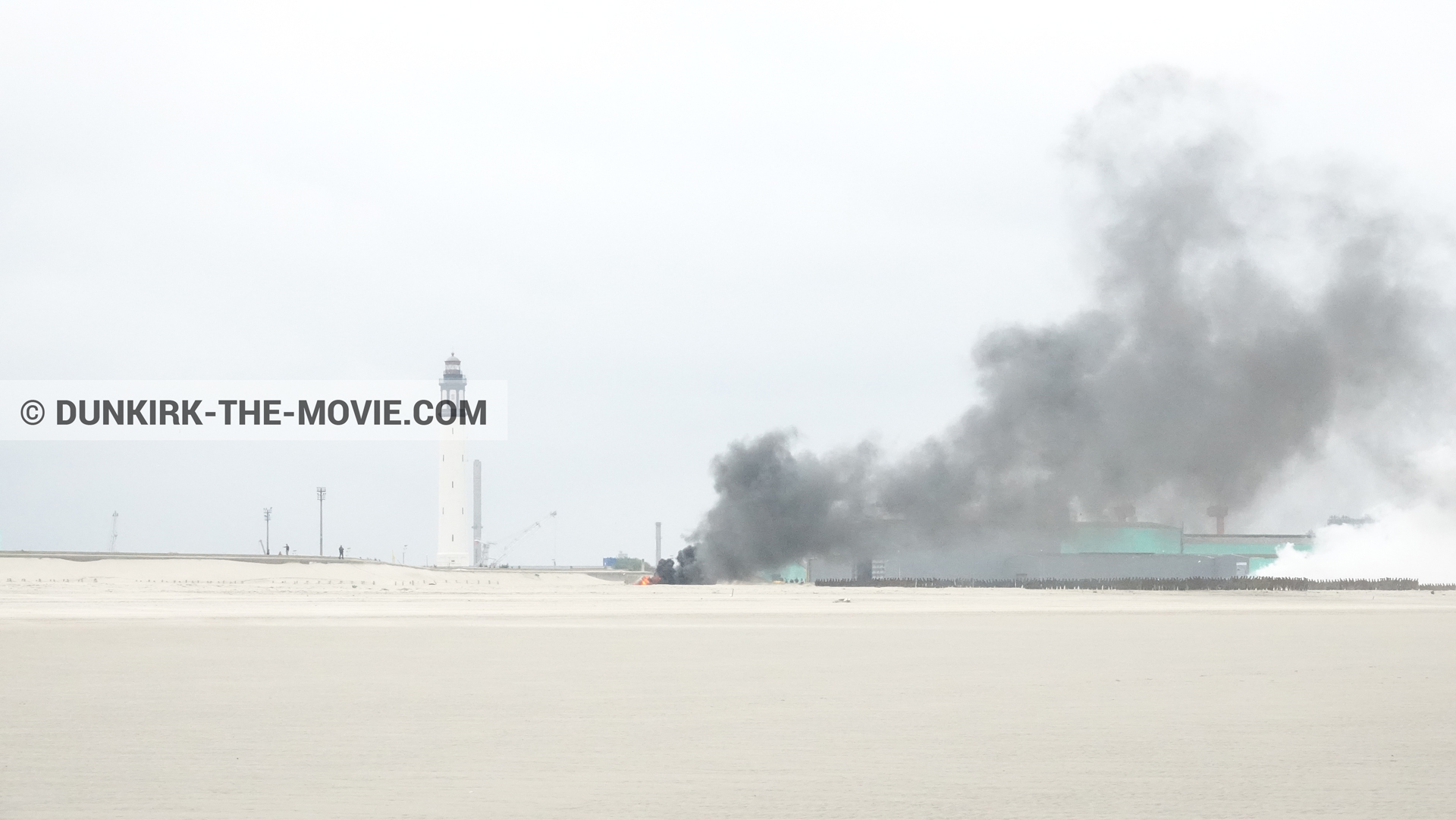 Picture with grey sky, black smoke, Dunkirk lighthouse, beach,  from behind the scene of the Dunkirk movie by Nolan