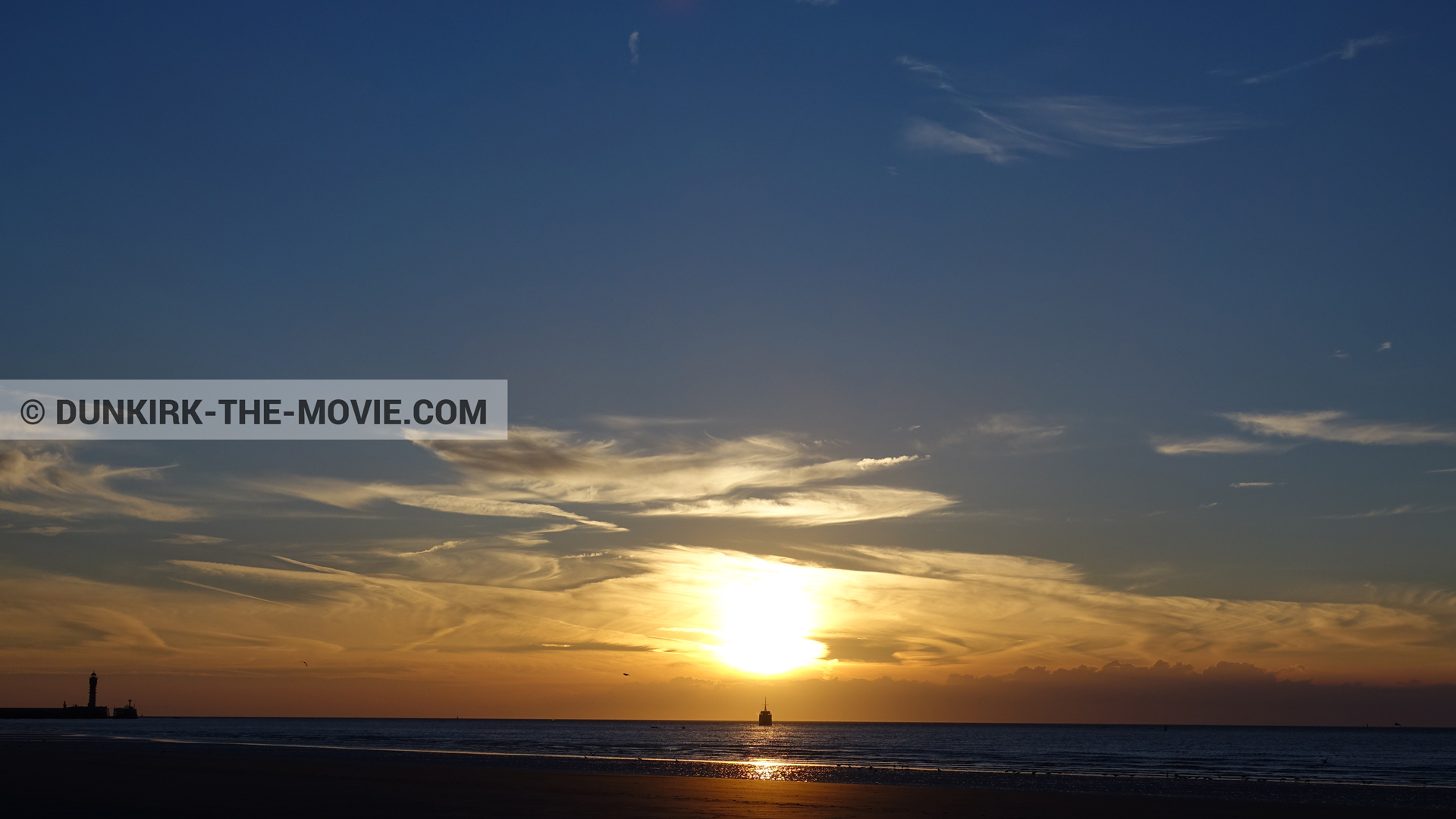 Photo avec ciel bleu, ciel orangé, mer calme, phare de St Pol sur Mer,  des dessous du Film Dunkerque de Nolan