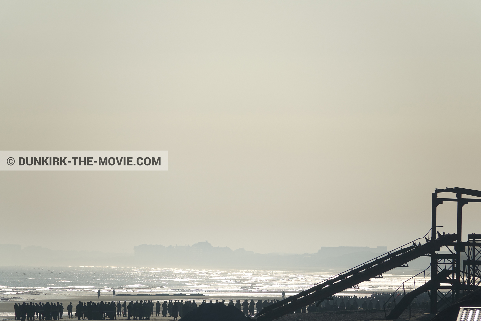 Photo avec ciel orangé, décor, figurants, plage,  des dessous du Film Dunkerque de Nolan