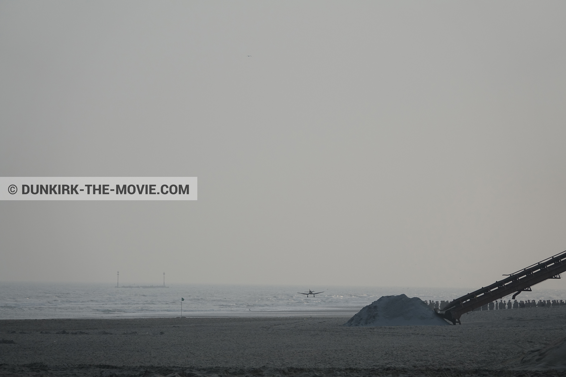 Picture with plane, grey sky, decor, supernumeraries, beach,  from behind the scene of the Dunkirk movie by Nolan
