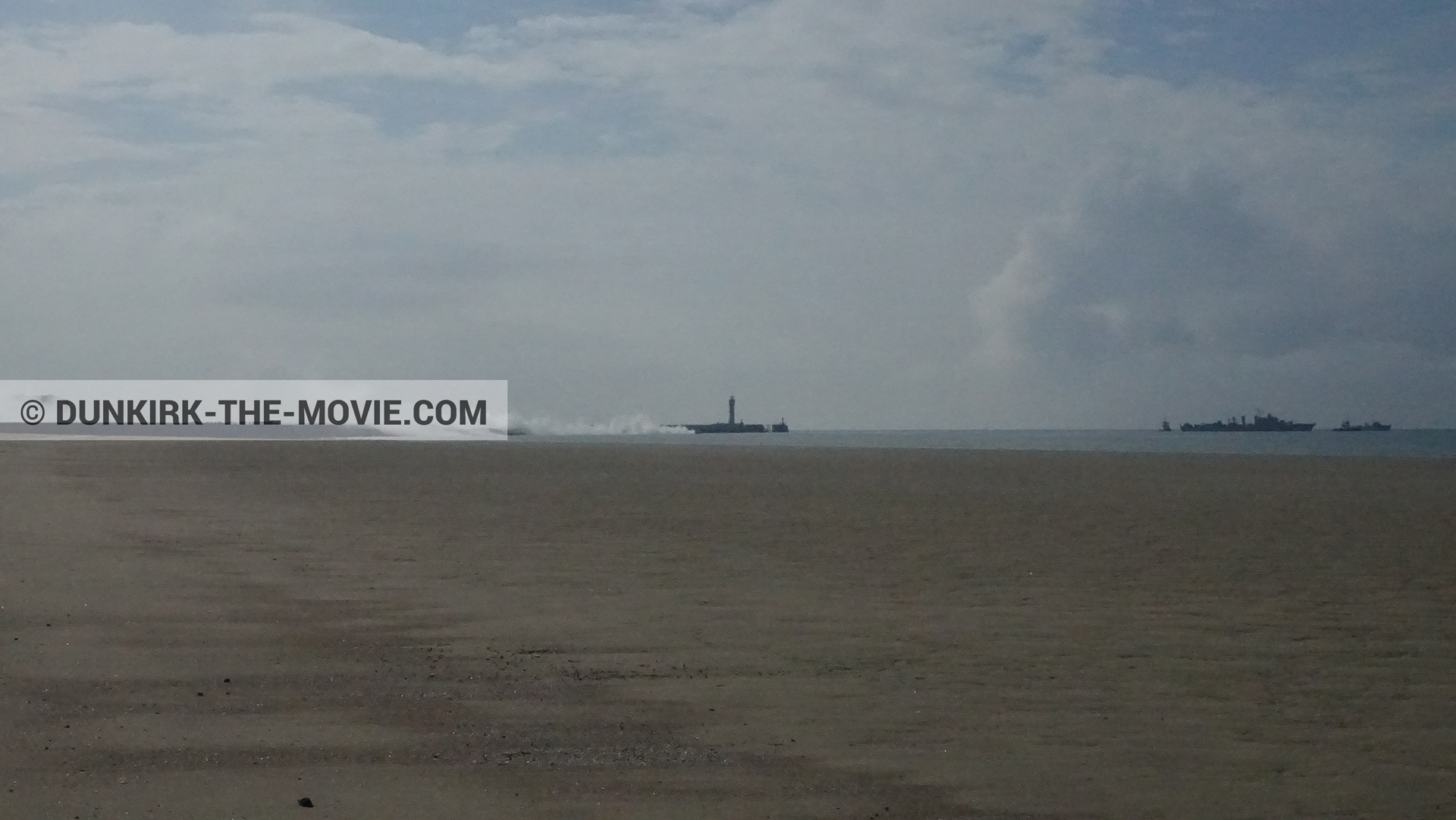 Picture with cloudy sky, white smoke, beach,  from behind the scene of the Dunkirk movie by Nolan
