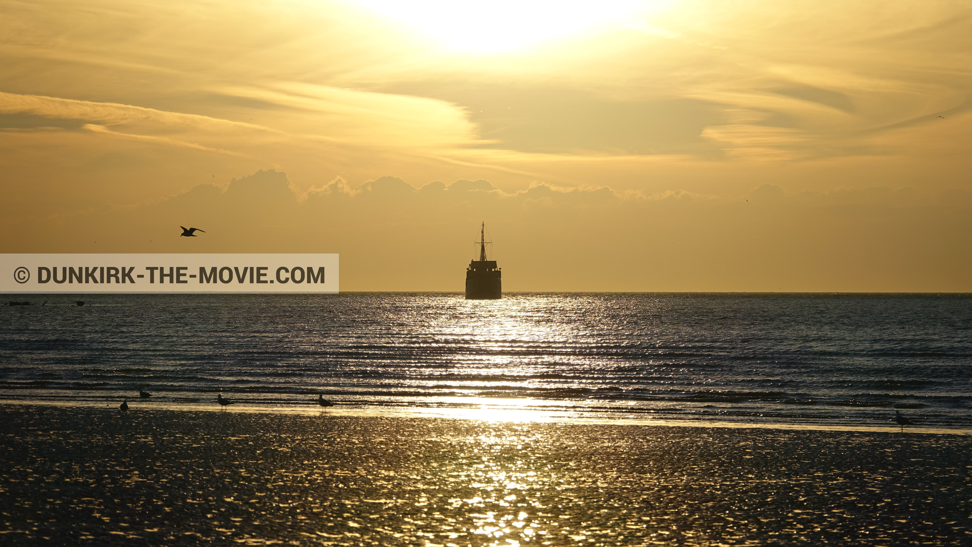 Picture with beach, calm sea, orange sky, boat,  from behind the scene of the Dunkirk movie by Nolan