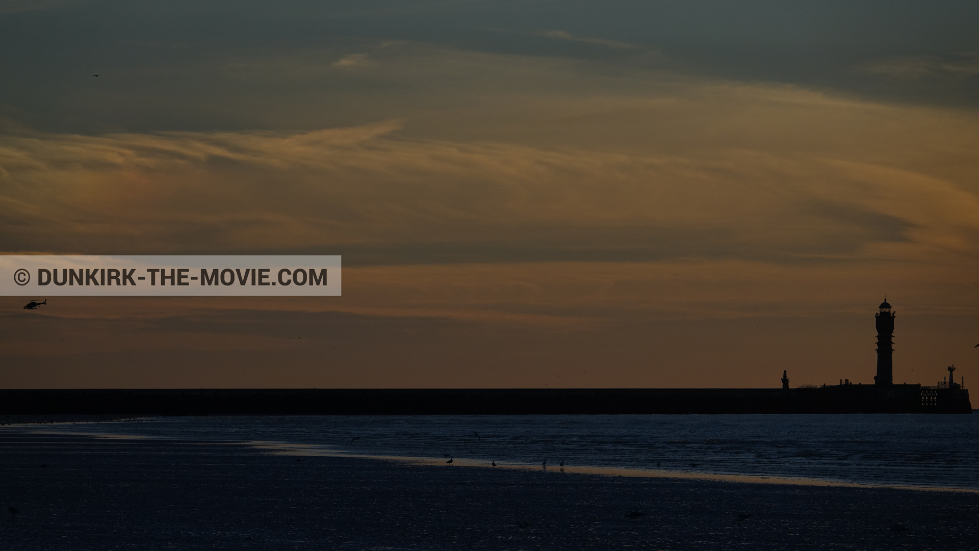 Picture with orange sky, helicopter camera, St Pol sur Mer lighthouse,  from behind the scene of the Dunkirk movie by Nolan